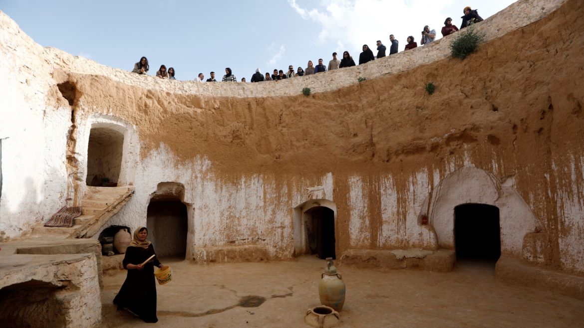 Tunisian tourists watch as Saliha Mohamedi, 36, walks around her troglodyte house on the outskirts of Matmata, Tunisia, February 4, 2018.
