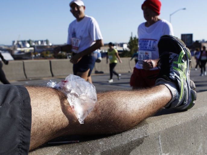 Runners walk by Javier Rancel from Venezuela, as he rests his injured knee on the Pulaski Bridge during the 2011 New York City Marathon in New York November 6, 2011. REUTERS/Shannon Stapleton (UNITED STATES - Tags: SPORT ATHLETICS)