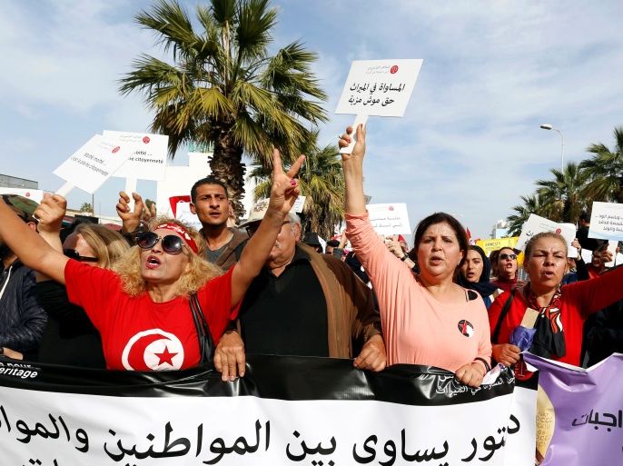 Protesters shout slogans during a march, demanding equal inheritance rights for women, in Tunis, Tunisia March 10, 2018. The placard (L) reads