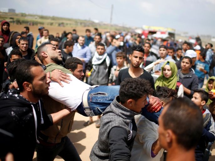 ATTENTION EDITORS - VISUAL COVERAGE OF SCENES OF INJURY OR DEATH A wounded Palestinian is evacuated during clashes with Israeli troops, during a tent city protest along the Israel border with Gaza, demanding the right to return to their homeland, east of Gaza City March 30, 2018. REUTERS/Mohammed Salem
