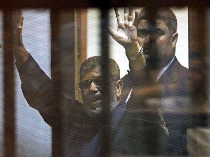 Deposed Egyptian President Mohamed Mursi greets his lawyers and people from behind bars after his verdict at a court on the outskirts of Cairo, Egypt June 16, 2015. An Egyptian court sentenced deposed President Mohamed Mursi to death on Tuesday on charges of killing, kidnapping and other offences during a 2011 mass jail break.The general guide of the Muslim Brotherhood, Mohamed Badie, and four other Brotherhood leaders were also handed the death penalty. More than 80 ot
