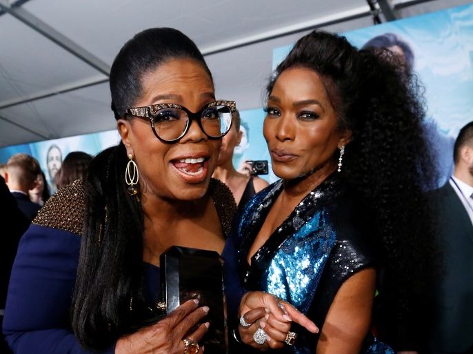 Cast member Oprah Winfrey (L) and actor Angela Bassett pose at the premiere of