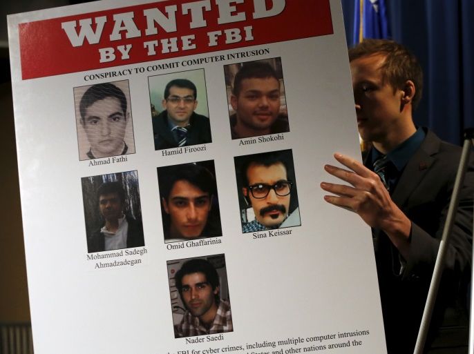An aide unveils a wanted poster before U.S. Attorney General Loretta Lynch and Federal Bureau of Investigation Director James Comey hold a news conference to announce indictments on Iranian hackers for a coordinated campaign of cyber attacks in 2012 and 2013 on several U.S. banks and a New York dam, at the Justice Department in Washington March 24, 2016. REUTERS/Jonathan Ernst