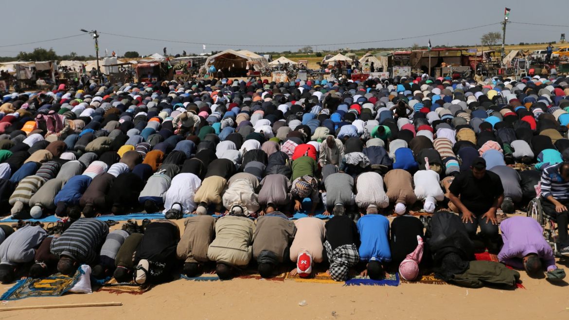 Palestinians perform Friday prayers during a protest demanding the right to return to their homeland, at the Israel-Gaza border in the southern Gaza Strip April 6, 2018. REUTERS/Ibraheem Abu Mustafa