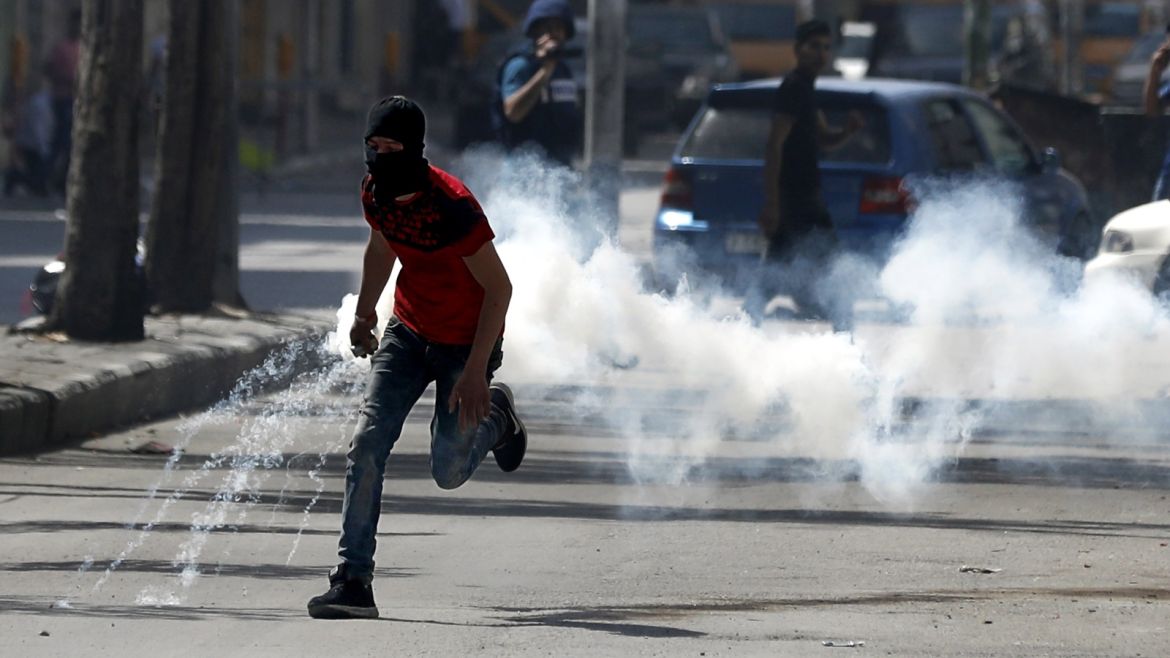 epa06650012 A Palestinian protester throws back a tear gas grenade fired by Israeli troops, during clashes in the West Bank city of Hebron, 06 April 2018. Protests in various locations in the West Bank are held in solidarity with Gaza and against the decision by US President Donald Trump to recognize Jerusalem as the capital of Israel. Islamist Hamas group that rules the coastal enclave of Gaza called for another protest on 06 April near the border with Israel, a week after 18 Palestinians were killed in clashes with Israeli forces during a march toward the border with the Israeli territory to commemorate their Land Day on 30 March. EPA-EFE/ABED AL HASHLAMOUN