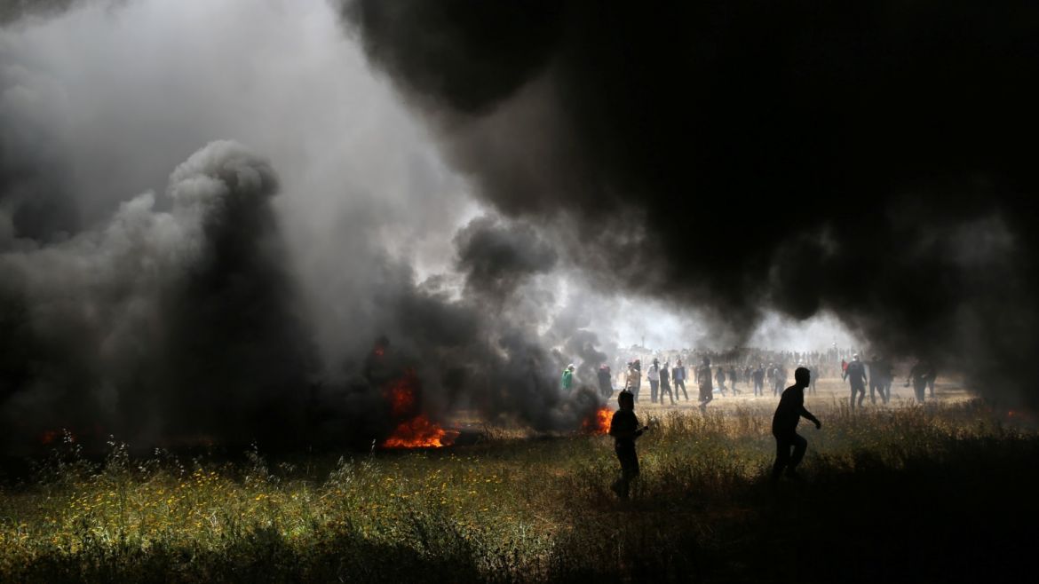 Smoke rises from burning tires as Palestinian demonstrators are seen during clashes with Israeli troops at the Israel-Gaza border at a protest demanding the right to return to their homeland, in the southern Gaza Strip April 6, 2018. REUTERS/Ibraheem Abu Mustafa