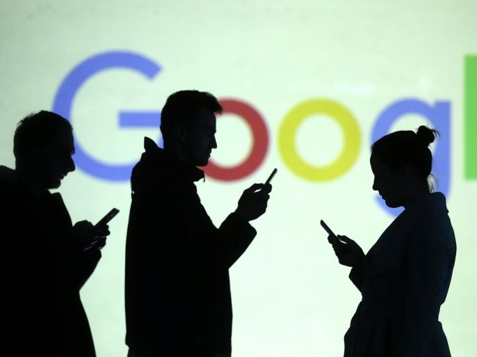 Silhouettes of mobile users are seen next to a screen projection of Google logo in this picture illustration taken March 28, 2018. REUTERS/Dado Ruvic/Illustration