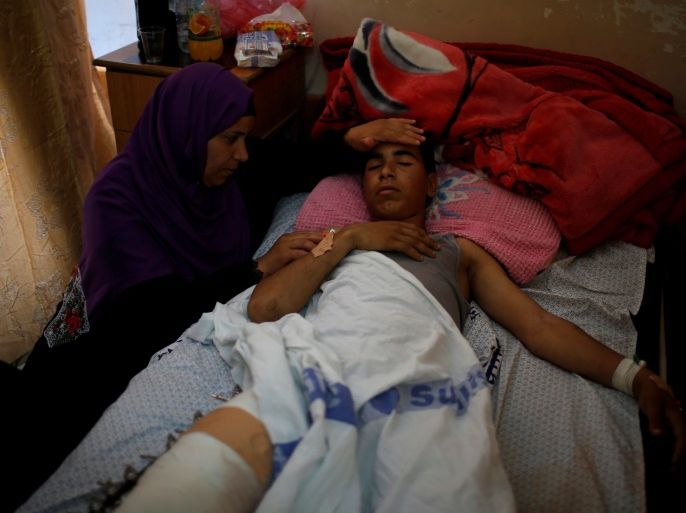 The mother of an injured Palestinian sits next to him as he lies on a bed at a hospital in Gaza City May 15, 2018. REUTERS/Mohammed Salem