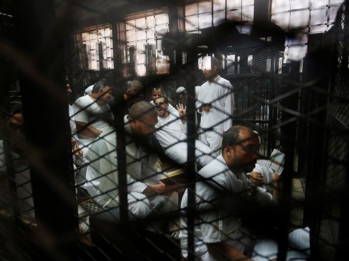 A Muslim Brotherhood member laughs behind bars as he gestures with the Rabaa sign, symbolizing support for the Muslim Brotherhood, during the trial of 738 brotherhood members for their armed sit-in at Rabaa square, at a court on the outskirts of Cairo, Egypt May 31, 2016. REUTERS/Amr Abdallah Dalsh