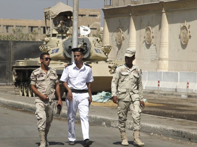 Police and army soldiers are seen in front of a tank as they guard outside Tora prison, where Al Jazeera television journalists Mohamed Fahmy and Baher Mohamed were held and are having their retrial, in Cairo, Egypt, July 30, 2015. A Cairo court session which had been expected to deliver a verdict on Thursday in the retrial of Al Jazeera television journalists has been adjourned, Al Jazeera said on its Twitter feed. The journalists are charged with aiding a terrorist or