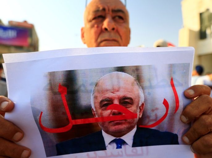 A protester holds a picture of Iraqi Prime Minister Haider al-Abadi with