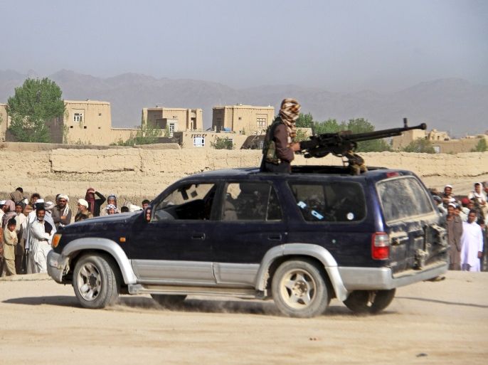 A member of the Taliban insurgent (top) and other people stand at the site of the execution of three men, accused of murdering a couple during a robbery, in Ghazni Province April 18, 2015. The Taliban announced the execution of the three men accused of murdering a couple during a robbery, saying they had been tried by an Islamic court. The killing was carried out in front of a crowd by Taliban fighters who fired at the men with AK-47s, according to a Reuters witness. Fo