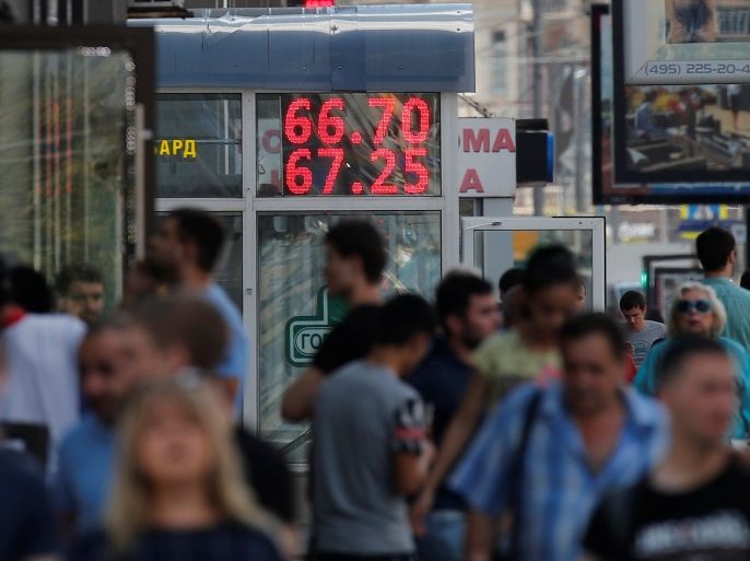 Pedestrians walk by an electronic board showing currency exchange rates of the U.S. dollar against Russian rouble in Moscow, Russia August 10, 2018. REUTERS/Maxim Shemetov