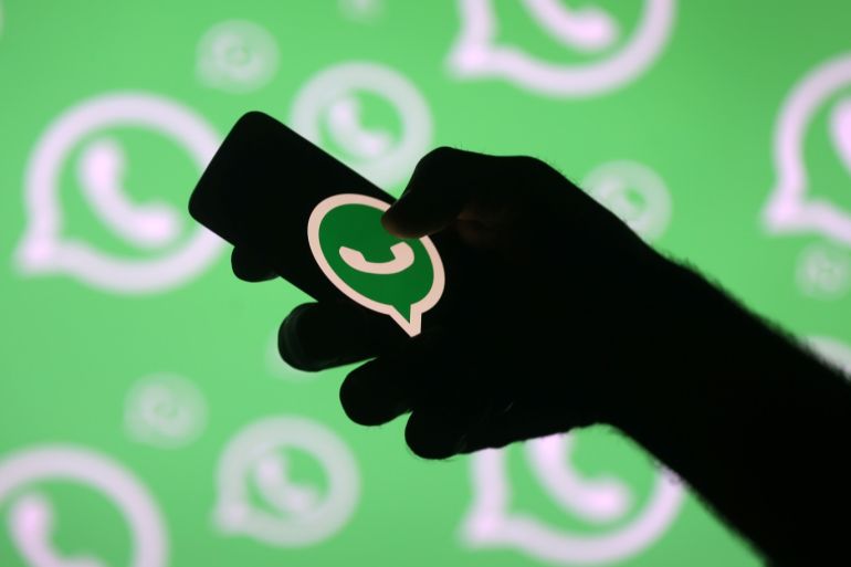 A man poses with a smartphone in front of displayed Whatsapp logo in this illustration September 14, 2017. REUTERS/Dado Ruvic