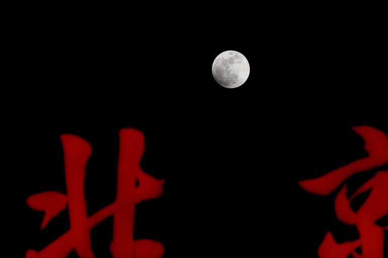 The super blue moon rises over Chinese signs reading