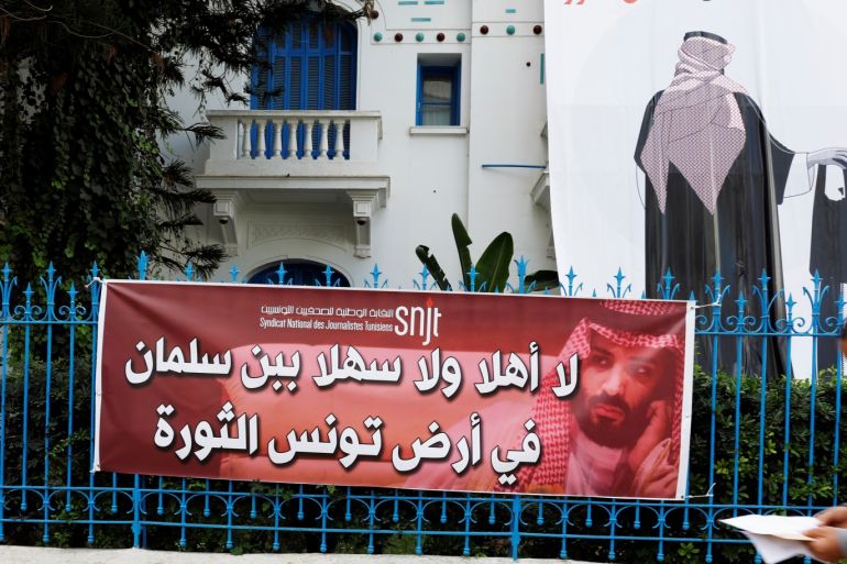 A man walks in front of a banner depicting an image of Saudi Crown Prince Mohammed bin Salman holding a chainsaw, near the Union of Tunisian Journalists headquarters in Tunis, Tunisia, November 26, 2018. The banners read ''no to the desecration of Tunisia, the land of the revolution'' (top R) and