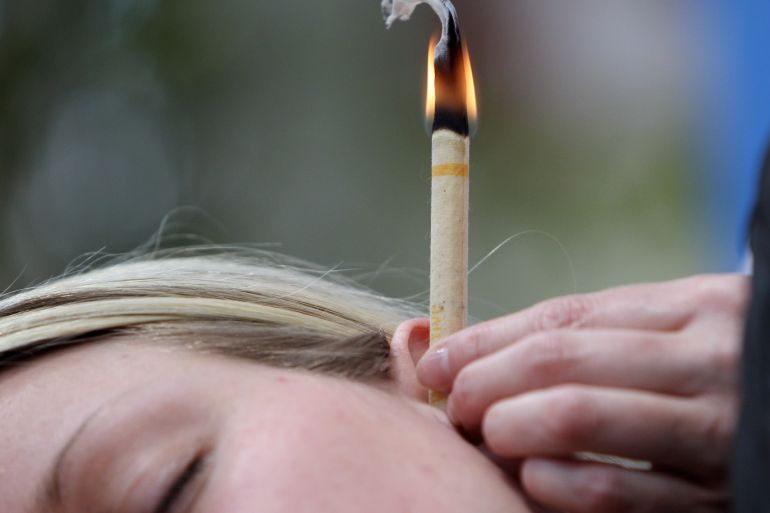 NUREMBERG, GERMANY - FEBRUARY 16: An earcandle burns in the ear of a woman during the Vivaness trade fair for natural personal care and wellness that is part of the world organic trade fair BioFach 2011on February 16, 2011 in Nuremberg, Germany. Ear candling is an alternative medicine practice claiming to improve general health. Critics say that according to medical researchers the so called thermal-auricular therapy is ineffective. Some 2500 exhibitors from over 80 countries present their products for the green market until February 19, 2011. (Photo by Miguel Villagran/Getty Images)