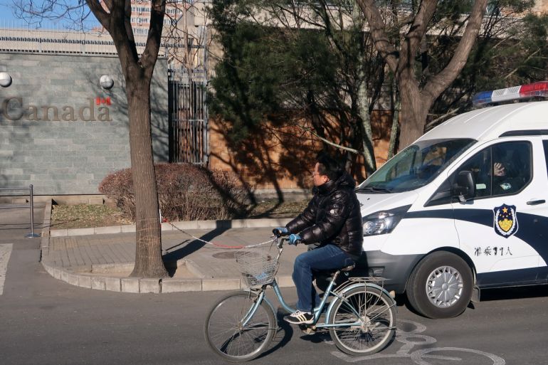 A man rides his bicycle past a police vehicle near the embassy of Canada in Beijing, China December 12, 2018. REUTERS/Martin Pollard