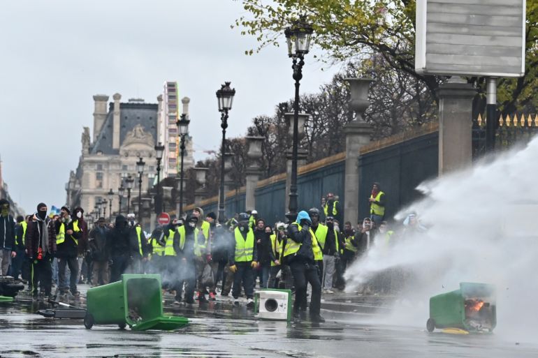 Yellow vest protest against rising fuel taxes in Paris- - PARIS, FRANCE - DECEMBER 01: Yellow vests (gilets jaunes) protesters protect themselves against fire tear gas and water cannon during clash with riot police on Rue de Rivoli, as part of demonstration against rising fuel taxes in Paris, France on December 01, 2018.