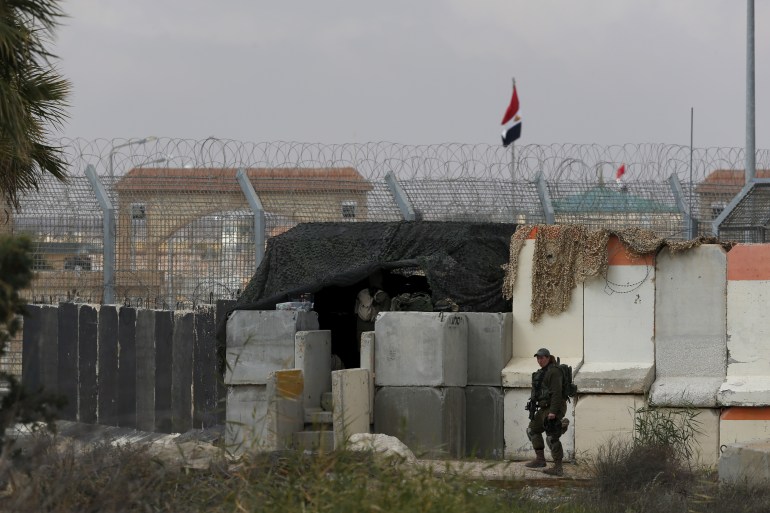 An Israeli soldier stands next to concrete barriers near Israel's border fence with Egypt's Sinai peninsula, in Israel's Negev Desert