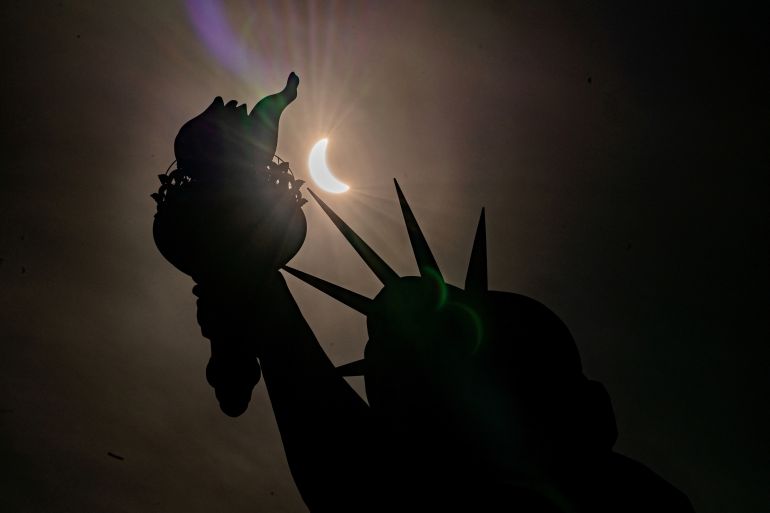 The Statue of Liberty is seen during a partial solar eclipse, where the moon partially blocks out the sun, at Liberty Island in New York City, U.S., April 8, 2024. REUTERS/David Dee Delgado TPX IMAGES OF THE DAY