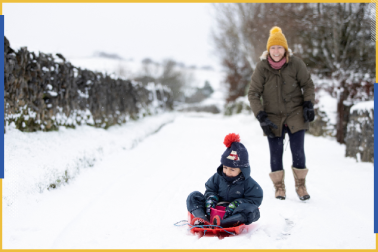Max rides on a sledge on the snow while his mother Amanda looks on, as the cold weather continues in Sparrowpit, Derbyshire, Britain, January 7, 2022. REUTERS/Molly Darlington