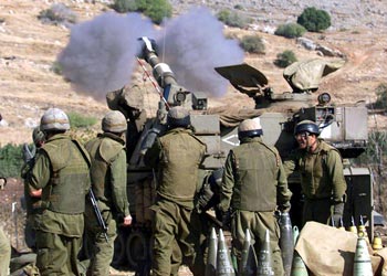 عدد من الجنود الإسرائيليين يقفون بجانب قطعة مدفعية تطلق النيران تجاه أهداف لحزب الله على الحدود الإسرائيلية اللبنانية