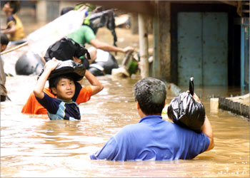 إندونيسيون يعبرون مياه الفيضان التي غمرت ساحة مجمع سكني في العاصمة جاكرتا