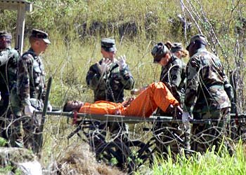 جنديان أميركيان يعيدان أسيرا مصابا إلى زنزانته في معسكر إكس راي بقاعدة غوانتانامو في كوبا عقب إجراء تحقيقات معه