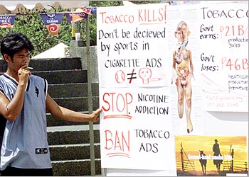 عامل فلبيني يقرأ إعلانات تحذر من خطر التدخين على الصحة في مانيلا في إطار حملة نظمها قسم الصحة الفلبيني بمناسبة اليوم العالمي لمكافحة التدخين
