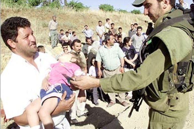 فلسطيني يشرح لجندي إسرائيلي حالة طفله المريض ليسمح له بالعبور عند مدخل بلدة الخضر قرب بيت لحم شمالي الخليل