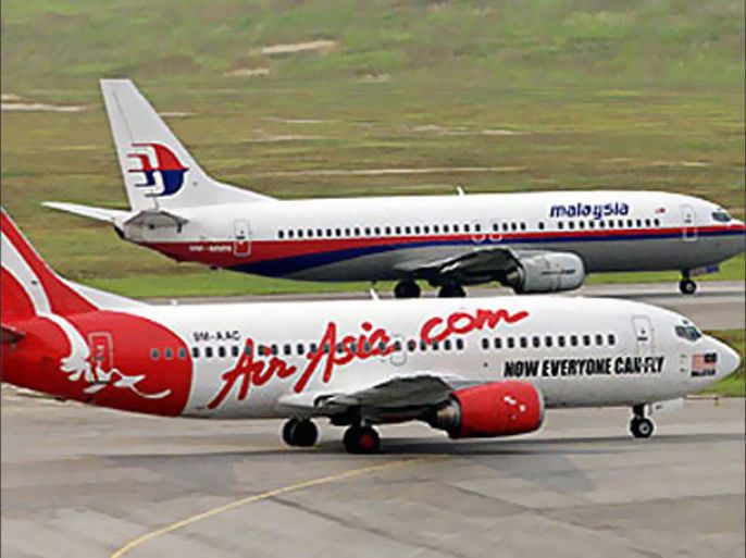 An Air Asia aircraft passes a Malaysian Airline System (MAS) plane at Kuala Lumpur International Airport August 13, 2002. MAS is locked in a heated price war with rival domestic carrier Air Asia, forcing the government to step in to diffuse the row that could spell the end for budding Air Asia. REUTERS
