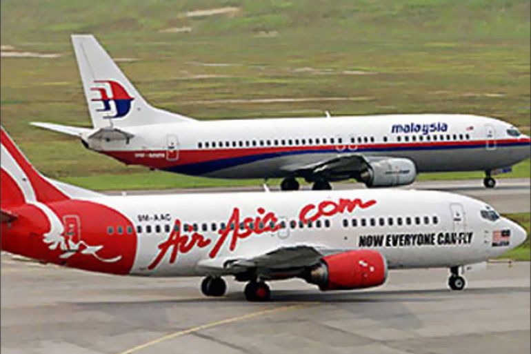 An Air Asia aircraft passes a Malaysian Airline System (MAS) plane at Kuala Lumpur International Airport August 13, 2002. MAS is locked in a heated price war with rival domestic carrier Air Asia, forcing the government to step in to diffuse the row that could spell the end for budding Air Asia. REUTERS