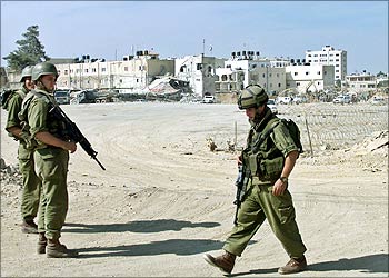 Israeli soldiers patrol in front of the destroyed compound of Palestinian President Yasser Arafat in the West Bank City of Ramallah October 6, 2002. European Union foreign policy Chief Javier Solana held talks with Israeli and Palestinian officials on Sunday, kicking off a fresh round of international diplomacy aimed at staunching two years of bloodshed. REUTERS/Osama Silwadi