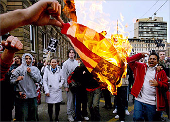 Anti-war demonstrators burn the U.S. flag during a protest against war in Iraq in Glasgow, Scotland March 20, 2003. U.S. forces on Thursday launched air strikes and artillery fire into southern Iraq and fought the first reported ground combat of the war as cruise missiles hit Baghdad, according to eyewitness media reports. REUTERS/Jeff J Mitchell