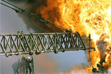 Kuwaiti firefighters secure a burning oil well in the Rumaila oilfields, March 27, 2003, set ablaze by Iraqi military forces. Efforts are
