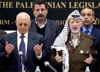 Palestinian President Yasser Arafat and parliament speaker Ahmed Korei pray at the start of a session of the Palestinian Legislative Council to approve the position of Palestinian Authority prime minister in a meeting held in the West Bank City of Ramallah March 10, 2003. Palestinian President Yasser Arafat called on Monday for a swift resumption of peace talks with Israel and condemned Palestinian militant attacks on Israeli civilians. REUTERS/Ammar Awad