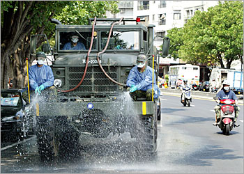 Taiwan soldiers disinfect a street of Taipei's Wan Hwa district to prevent the spread of Severe Acute Respiratory Syndrome (SARS) on May 12, 2003. Authorities are worried the flu-like virus has spread into the community after a raft of infections were discovered at a public housing block and two hospitals in the area. The military sent 2,000 soldiers to disinfect the neighbourhood. REUTERS/Richard Chung