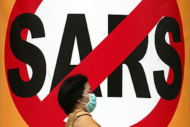 A masked Taiwanese woman strolls past a huge anti-SARS sign at a shopping mall in Taipei, May 27, 2003. Taiwan, which has the world's third-worst outbreak of Severe Acute Respiratory Syndrome (SARS), says the disease is under control as the island reported 11 new probable cases on Tuesday, taking the total to 596. REUTERS/Richard Chung