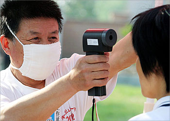F_A school worker checks a student with a thermometer gun prior to entering the school to sit for the college-entrance examinations in Beijing, 07 June 2003. Some 6.13 million high school students across China were taking the most important test of their lives on 07 June, one which the government has insisted on not postponing despite the SARS crisis. AFP PHOTO