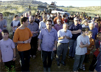 Jewish settlers hold a prayer as they block army trucks after Israeli soldiers removed a tower from the outpost of Amona north of the West Bank city of Ramallah 09 June 2003. Israel started dismantling settlement outposts and Palestinian prime minister Mahmud Abbas reiterated his commitment to the US-backed peace roadmap on Monday, as both sides appeared intent on implementing the blueprint despite opposition from hardliners. AFP PHOTO/OREL COHEN