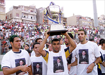 f_Imad al-Miry of Beirut's Olympique team lifts the trophy after his team won the Lebanese championship in Beirut 29 June 2003 as teammates Yussef Mohammed (L) and South African Pierre Issa (R) look on. Olympique took the title despite losing 2-0 to rival Beiruti team al-Nejma (Star). AFP PHOTO/Haitham MUSSAWI