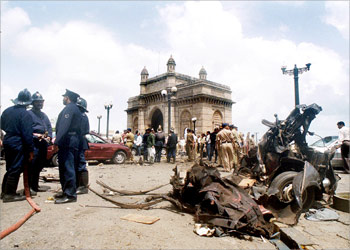 Bombay police and firemen conduct investigations at the site of a powerful car bomb explosion at the Gateway of India (background) in Bombay, 25 August 2003. Two powerful explosions at seperate places killed at least 44 people and injured over 100 people
