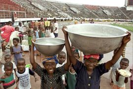 Liberian children carry wash-basins filled with water in a stadium in which they live and which is used as a camp for displaced people, on the outskirts of Monrovia, August 22, 2003. Liberia's warring factions on Thursday named a low-profile businessman seen as a shrewd consensus builder to guide their broken West African state out of 14 years of anarchy and towards elections. REUTERS/Vasily Fedosenko