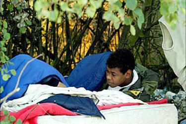 r: A Sudanese asylum seeker sleeps on a piece of waste land near Calais' city hall, northern France