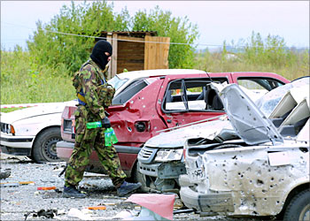 R_A member of the local security forces walks past wrecked cars at the site of a blast near a governmental building in the Ingush capital of Magas September 15, 2003. In the latest of a series of attacks at least two people were killed and dozens injured on Monday in an apparent suicide attack in the city of Magas, the newly established capital of Ingushetia province, which neighbours war-torn Chechnya. REUTERS/stringer