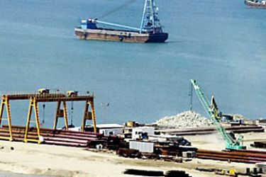 In this photo taken, 16 August 2003 crane digs away at the shoreline as a barge mounted crane sails nearby in the Pakistani town of Gwadar, 675 kilometers (405 miles) west of Karachi.