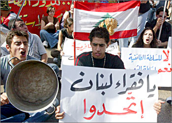 Lebanese youths, hoding anti-poverty banners and national flags, protest during a general strike in Beirut 23 October 2003. Lebanon came to a standstill today as a general strike called by the trade union confederation CGTL crippled the education, transport and banking sectors. The unions are demanding the lifting of a salary freeze in effect since 1996, oppose a planned increase in VAT and want the government to increase social spending in the draft