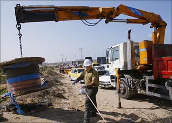 A Palestinian worker fixes an power network along a major road that links various parts of the Gaza Strip, near the Jewish settlement of Netzarim 08 October 2003. Israeli troops opened the road for one hour only today, according to Palestinian sources. The Israeli army has maintained a tight closure around the West Bank and Gaza Strip since a suicide attack in the northern Israeli city of Haifa on the weekend which killed 19 people as well as the female Islamic Jihad bomber