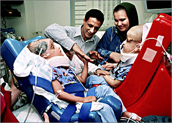 This handout photo from the Children's Medical Center of Dallas shows Egyptian former conjoined twins Mohamed Ibrahim (L) and Ahmed Ibrahim (R) viewing each other for the first time since their separation, with father Mohamed Ibrahim (C-L), mother Sabah Abou Al Wafa (C-R) and brother Mahmoud Ibrahim (2nd L) at the Children's Medical Center in Dallas, Texas, 24 October 2003. Ahmed and twin Mohamed Ibrahim were born two years ago, joined at the crowns of their heads. They endured marathon surgery at the hospital October 11 and 12 to separate them and give them a chance at normal development. AFP PHOTO/CHILDREN'S MEDICAL CENTER DALLAS